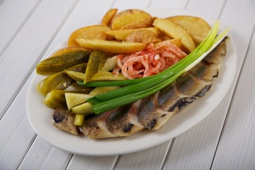 Delicious appetizer of pickles, potatoes, onions and salted fish all shot on a white background