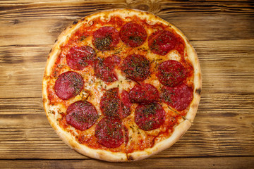 Delicious fresh pizza with sausage and cheese on a wooden table. Top view