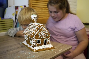 Children eat Christmas gingerbread cookies. Christmas gingerbread cookies in the form of a house. The child eats a Christmas carrot with cream. Cream for gingerbread.