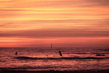 Fototapeta na wymiar ligne de surfeur au coucher de soleil sur la plage de pontaillac 