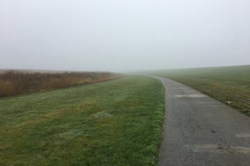 A Dyke in the Mist on a foggy day in East Frisia, in the North of Germany near Pilsum. Northsea coast