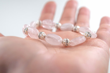 Bracelet made with pink quartz beads and silver beads in the female hand