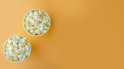 Fresh popcorn in white box on a orange background. Cinema snack concept. The food for watching a movie and entertainment. Copy space for text, top view, flat lay.