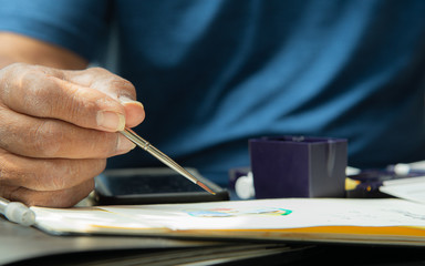 Close up Artist hand with blue shirt holding paint brush working art project during work from home because of COVID-19