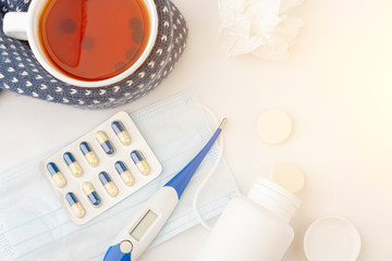 Cup of tea, thermometer, crumpled napkin, medical mask