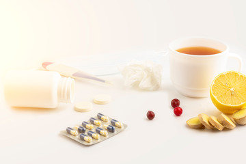 Cup of tea with cranberries, ginger, lemon and pills on white, close up. The concept of seasonal diseases and treatment of colds, flu, heat. Natural medicine vs conventional medicine