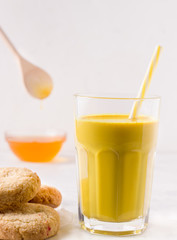 indian drink golden milk next to cookies and honey on a white background