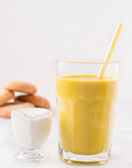 healthy latte with turmeric and spices on a white plate next to milk and cookies. golden milk