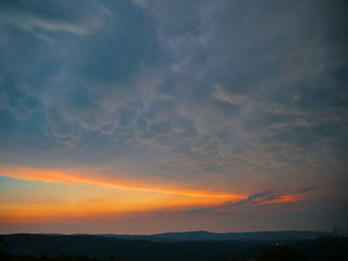 Dark mammatus clouds gather above the peaceful countryside at golden sunset.