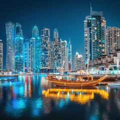 Foto op Canvas Multicolored lights of the night city in the Dubai Marina district. Stylized ancient Arabic ship Abra Dhow with lights in the foreground. © EdNurg