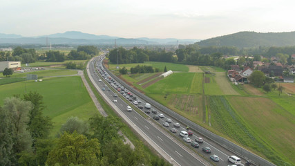 AERIAL: Flying along a busy highway full of rush hour traffic on a sunny day.