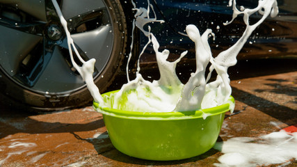 CLOSE UP: Detergent foam splashes after a sponge falls into a green container