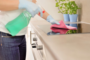 Woman in gloves cleaning kitchen.