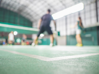 The shuttlecock is on the green badminton court floor. There is motion blur. The highlight is the...