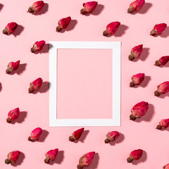 Flatlay of dried rose flowers on a pink background and white paper frame with copy space, hard flashlight