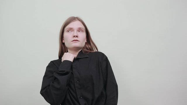 Disappointed young woman in fashion black shirt isolated on gray background in studio chocked herself with shirt. People sincere emotions, lifestyle concept.