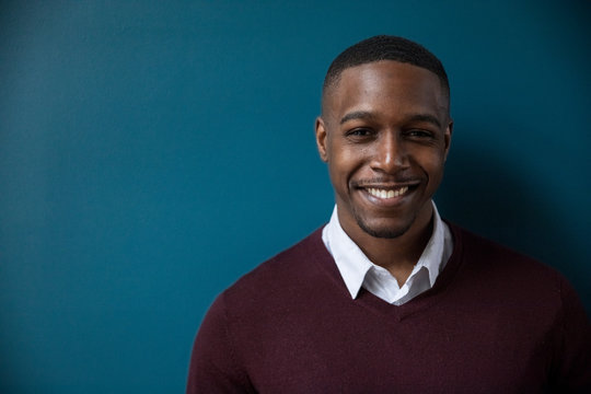 Portrait of confident smiling businessman standing against wall in darkroom at office