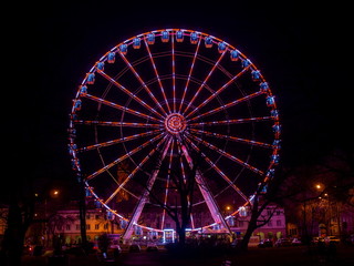 Red tone illuminated colorful illuminated ferris wheel at night
