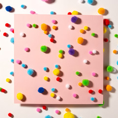 Holiday background with colorful soft fluffy balls for holiday decor, pink paper background