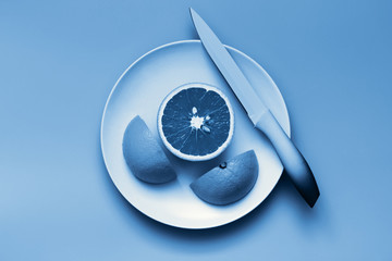 Classic blue orange, citrus fruit cut on plate. Color of the year 2020 toned