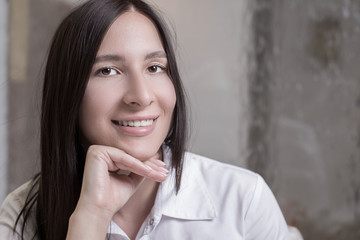 Portrait of a beautiful young brunette girl, in a white shirt with flawless hair. on a calm background.