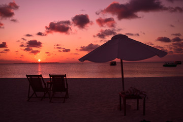View of umbrella and sunbeds facing the Indian Ocean and the beautiful sunset.