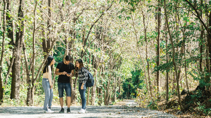 Group of Asian and European friends have outdoor adventure traveling in the forest on vacation with backpack, using map on smartphone for searching direction and find way out. Trail Trekking concept.