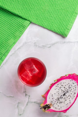 Glass of mango dragonfruit refresher drink on marble table with ice cubes. Copy space.