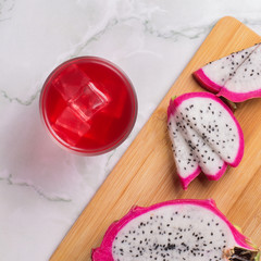 Glass of mango dragonfruit refresher drink on marble table with ice cubes. Copy space.