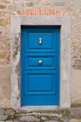 Old mediterranean blue door with marble jambs in the small village of Nicola in Italy