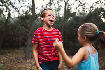 Two kids playing and dancing in the forest
