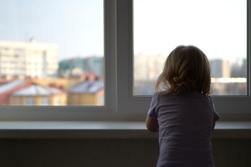 A little girl standing in front of a window
