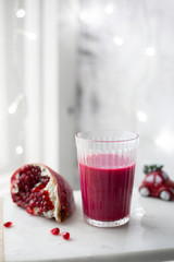 Fresh pomegranate juice in a glass on white marble background