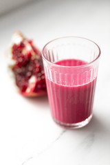 Fresh pomegranate juice in a glass on white marble background