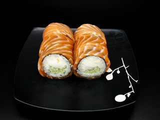 Philadelphia cheese roll on Japanese black plate on dark background