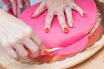 women preparing and decorating a cake with sugar paste