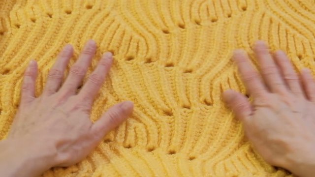 Yellow knitted warm sweater. Women's hands smooth out the sweater and consider the quality of the seams. Hobby and hand made concept