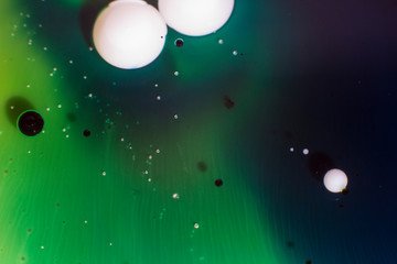 Green and blue oily ink with two white drops artistic texture with bubbles