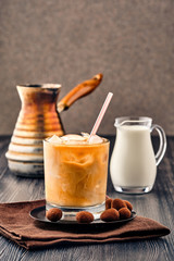 Iced coffee with cream on dark wooden background