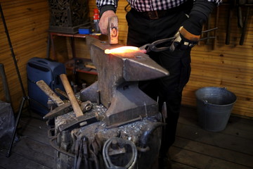 the blacksmith forges a glowing horseshoe