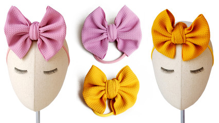 Handmade yellow bow and pink bow display on a mannequin head for DIY project. These hair bows are great for decoration and embellishment as hair accessories.