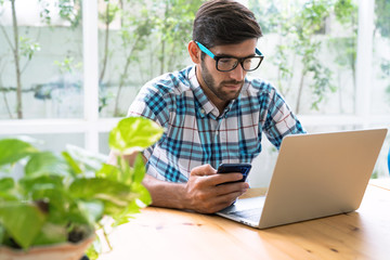 A young businessman dressed in casual clothes, working at his home during the holidays.