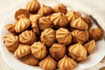 Cookies in a white plate on a white tablecloth