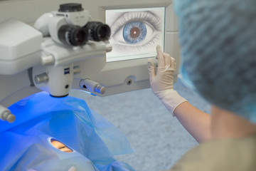 Doctor ophthalmologist, pressing the button on the control display to start a modern laser for the...