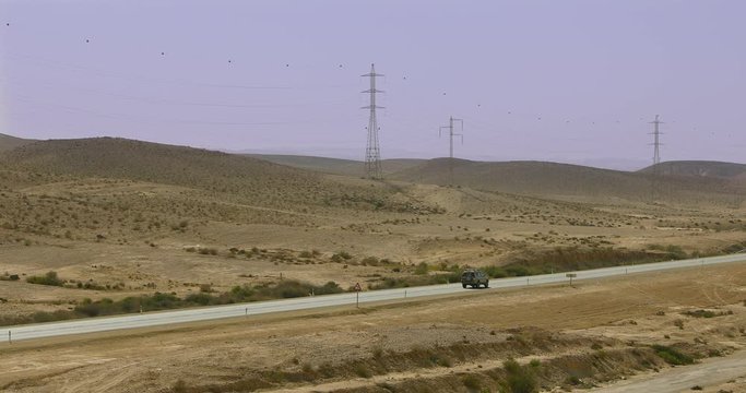 One off-road car moves along a highway in desert at winter