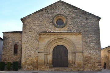 Fototapeta na wymiar Front view of the Romanesque church of Santa Cruz in Baeza with a woman coming out of a side alley
