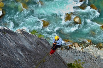 Climbing the majestic Star Chek multi-pitch route south of Whistler. Young man rappels beautiful climbing route above the wild river.