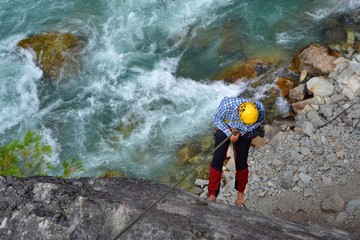 Climbing the majestic Star Chek multi-pitch route south of Whistler. Young man rappels beautiful climbing route above the wild river.