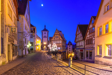 Fototapeta na wymiar Decorated and illuminated Christmas street with gate and tower Plonlein in medieval Old Town of Rothenburg ob der Tauber, Bavaria, southern Germany