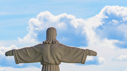 The copy of the sculpture of Christ the Savior spread his arms on blue sky background. Religion concept.